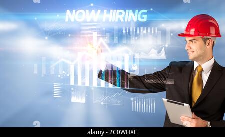 Gut aussehender Geschäftsmann mit Helm Zeichnung JETZT EINSTELLUNG Inschrift, Architektur Konzept Wipl Stockfoto