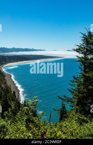 Vertikales Foto - Blick auf die zerklüftete Küste von Oregon an einem sonnigen Tag mit Nebel an Land in der Ferne. Stockfoto