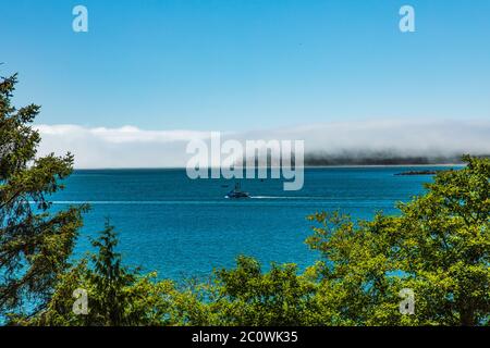 Fischerboot auf dem Weg zum Meer in Richtung einer Nebelwand entlang der zerklüfteten Küste in Oregon Stockfoto