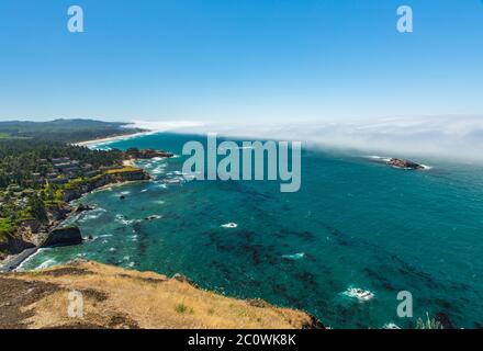 Landschaftlich schöner Blick vom Cape Foulweather auf den Nebel, der vom Meer in Richtung der zerklüfteten Küste in Oregon einrollt Stockfoto