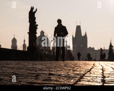 People walk on Charles bridge in early morning, Prague, Czech Republic. Focused on cobblestones. People and architecture are unfocused. Shallow depth of field. Stockfoto