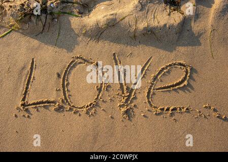 Das Wort Liebe von Hand in den Sand geschrieben. Stockfoto