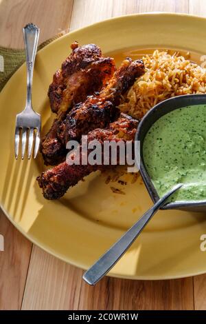 Peruanische Hühnerschenkel mit Aji verde grüner Koriander-Sauce und gebratenem Reis Stockfoto