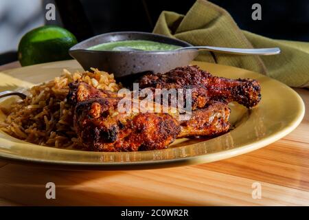 Peruanische Hühnerschenkel mit Aji verde grüner Koriander-Sauce und gebratenem Reis Stockfoto