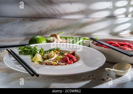 Traditionelle vietnamesische Pho bo-Rind-Nudelsuppe mit Nudeln Basilikum Koriander-Pilze und Bohnensprossen serviert Stockfoto