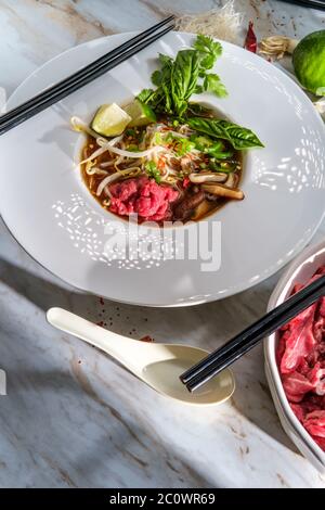 Traditionelle vietnamesische Pho bo-Rind-Nudelsuppe mit Nudeln Basilikum Koriander-Pilze und Bohnensprossen serviert Stockfoto