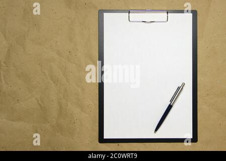 Ein Tablett mit einem weißen Blatt im A4-Format mit Stift auf einem beigen Bastelpapier. Konzept der Analyse, des Studiums, der aufmerksamen Arbeit. Stock Foto mit leerem Platz für Ihren Text und Design. Stockfoto