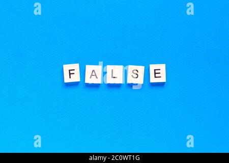 FALSCHE Wort Buchstaben auf blauem Hintergrund. Flaches Layout. Draufsicht. Stockfoto