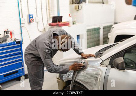 Afroamerikanischer Mechaniker Mann, der ein Auto schleift Stockfoto