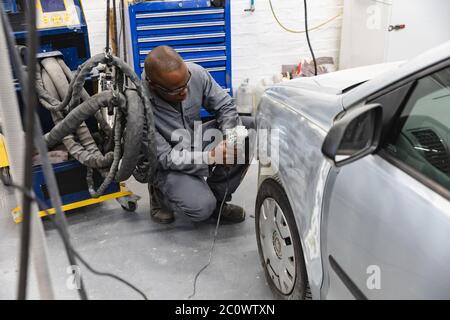 Afroamerikanischer Mechaniker Mann, der ein Auto schleift Stockfoto