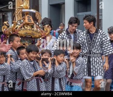 Kinder, die einen tragbaren Schrein oder Mikoshi in einer Straßenprozession während des Shibuya Mikoshi Parade Festivals, Tokio, Japan, tragen. Stockfoto