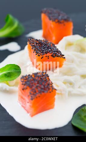 Lachsnüsse mit Mohn auf Stracciatella-Käse und Baldrian-Blättern Stockfoto