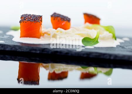 Lachsnüsse mit Mohn auf Stracciatella-Käse und Baldrian-Blättern Stockfoto