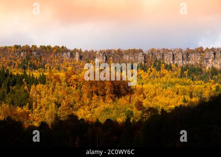Panoramablick auf Sandsteinfelsen inmitten eines bunten Herbstwaldes. Dramatische Aussicht am Abend. TiSA Rocks, aka Tiske Walls, Tschechisch-Sächsische Schweiz, Tschechien Stockfoto