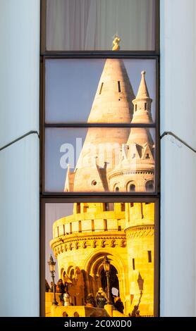 Detailansicht der verformten Reflexion der Fischerbastei, alias Halaszbastya, Märchentürme in den Fenstern des modernen Hotels. Architektonische Gestaltung der historischen Wahrzeichen und gehasst moderne Architektur des kommunistischen Ungarn. Budapest, Hauptstadt von Ungarn, Europa. UNESCO-Weltkulturerbe Stockfoto