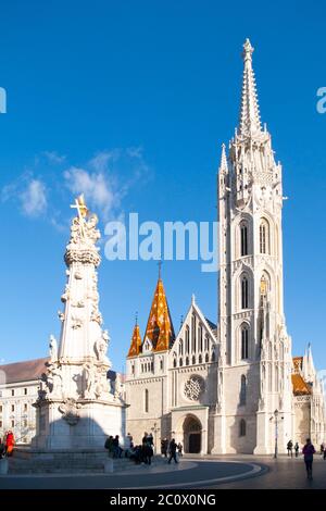 Römisch-katholische Matthias-Kirche und Heilige Dreifaltigkeit Plakette Säule in Fisherman's Bastion in Buda Castle District, Budapest, Ungarn, Europa. Sonniger Tagesfoto mit klarem blauen Himmel. Stockfoto