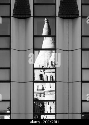 Detailansicht der verformten Reflexion der Fischerbastei, alias Halaszbastya, Märchentürme in den Fenstern des modernen Hotels. Architektonische Gestaltung der historischen Wahrzeichen und gehasst moderne Architektur des kommunistischen Ungarn. Budapest, Hauptstadt von Ungarn, Europa. UNESCO-Weltkulturerbe. Schwarzweiß-Bild. Stockfoto