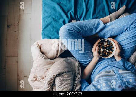 Foto von oben einer Frau im Pyjama mit gesunden Gewohnheiten, Getreide zu essen Stockfoto