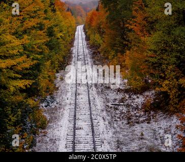 Autumn colors and fresh snowfall along railroad tracks in Michigan's Upper Peninsula, USA Stockfoto