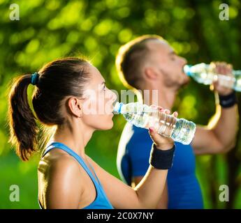 Mann und Frau Trinkwasser aus der Flasche nach dem Fitness Sport Training Stockfoto