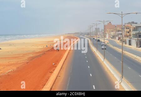 Fast leere Küstenstraße und ebenso leerer Strand im Viertel Guediawaye, Dakar, Senegal Stockfoto