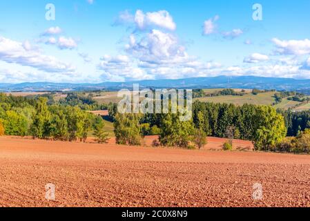 Typische rote Erde der Landschaft um Nova Paka. Landwirtschaftliche Landschaft mit Riesengebirge im Hintergrund. Tschechische Republik. Stockfoto