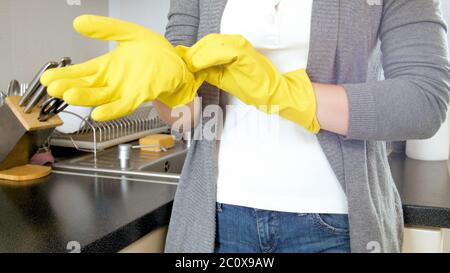 Junge Hausfrau setzen auf gelben Schutzgummi Handschuh vor Hausarbeit zu tun Stockfoto