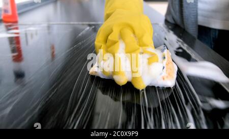 Nahaufnahme von yougn woamn in Gummihandschuhe Waschen Elektroherd mit Schwamm und Reinigungsmittel Stockfoto