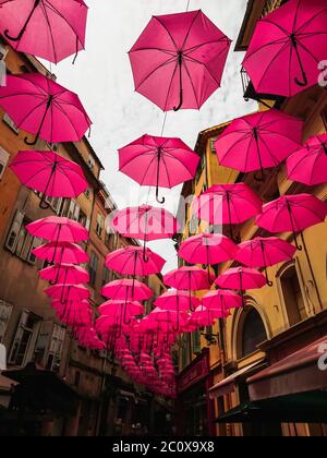 Rosa Regenschirme in einer Straße in der Altstadt von Grasse im Sommer, Frankreich Stockfoto