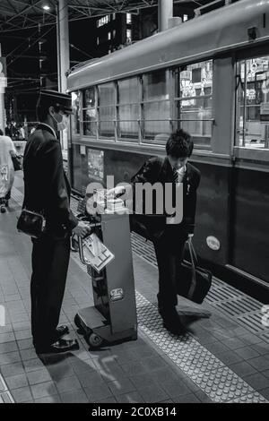 Controller Steuerung von Young mans Straßenbahntickets vor der Straßenbahn in Hiroshima Japan Stockfoto