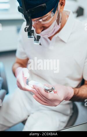 Zahnarzt bereitet eine Düse für einen Bohrer - Vorbereitung einer Zahnarztpraxis, um einen Patienten für die Zahnbehandlung zu erhalten Stockfoto