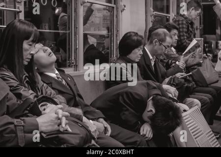 Passagiere müde von der Arbeit schlafen in einem späten Nachtzug in Hiroshima Japan Stockfoto