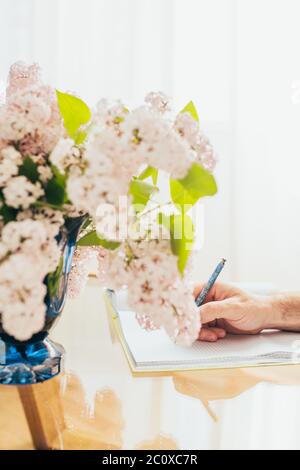Blumenstrauß Flieder auf dem Schreibtisch des Schriftstellers - morgens Inspiration für das Schreiben eines Buches Stockfoto
