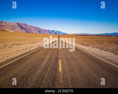 Die endlose, gerade Badwater Road führt durch die karge Landschaft des berühmten Death Valley, Kalifornien. Es ist einer der heißesten Orte in t Stockfoto