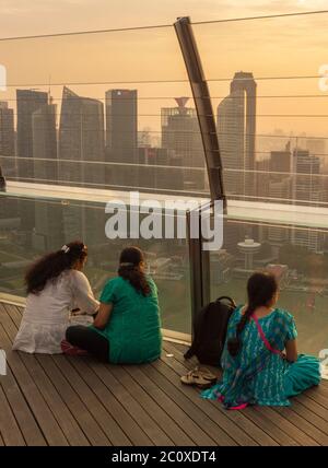 Frauen beobachten den Sonnenuntergang über der Skyline von Singapurs Innenstadt von der Terrasse des Marina Bay Sands Hotels aus. Singapur Stockfoto