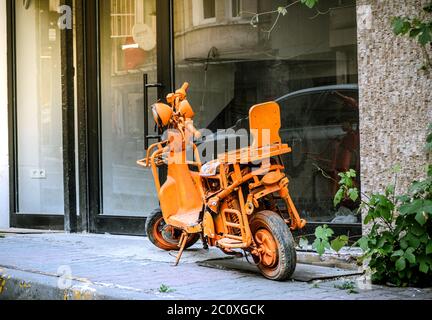 Sehr schäbig diy modifizierten Roller, Retro-City-Fahrrad, lackiert ganz orange, Phosphor, bleibt als ein unkonventioneller Gegenstand auf der Seite der Straße. Stockfoto