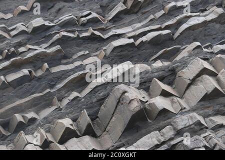 Gezackte dreieckige Felswand mit geometrischen Mustern Stockfoto