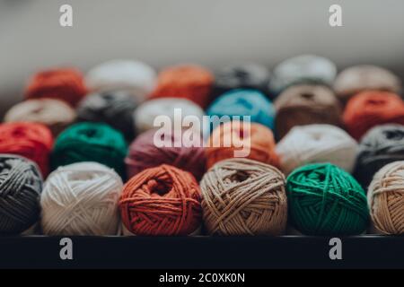 Nahaufnahme einer Schachtel mit 24 verschiedenfarbigen Skeins aus Amigurumi-Baumwollgarn, selektiver Fokus auf die nächste Reihe. Stockfoto