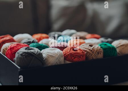 Nahaufnahme einer Box voller verschiedener Farbskeins aus Amigurumi-Baumwollgarn, selektiver flacher Fokus. Stockfoto