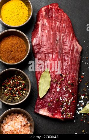 Gewürze in Schüsseln und rohes Flankensteak Stockfoto