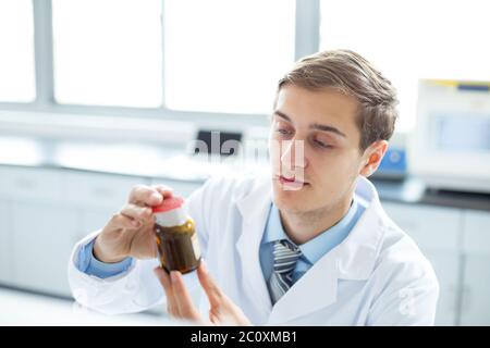 Junger schöner Mann, der chemische Experimente im modernen Labor macht Stockfoto