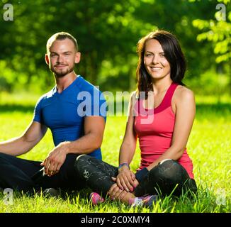 Junger Mann und Frau beim Yoga im sonnigen Sommerpark Stockfoto