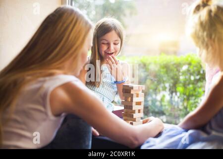 Glückliche Mutter mit zwei Kindern, die den Holzklötze-Turm spielen Stockfoto