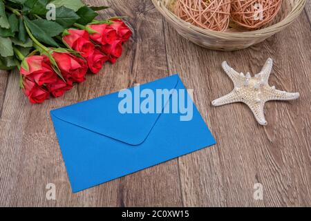 Blauer Umschlag, Seesterne und Rosen auf Holzhintergrund Stockfoto