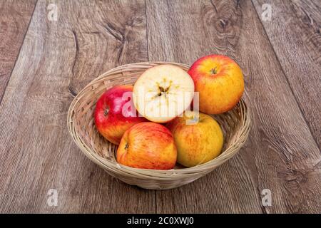 Äpfel in einen gestrickten Schüssel auf einem hölzernen Hintergrund Stockfoto