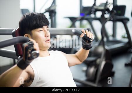 Die Jungen gut aussehenden asiatischer Mann arbeitet in modernen gynm Stockfoto