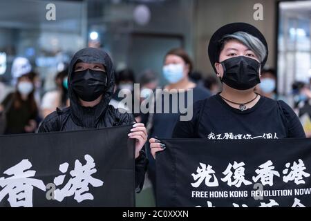 Hongkong, China. Juni 2020. Zwei Demonstranten, die am 12. Juni 2020 bei einer Kundgebung im Bezirk Shatin in Hongkong Protestflaggen hielten. Tausende von Hongkongern sangen am 12. Juni Protesthymne und skandierten Parolen in der Stadt, als sie den einjährigen Jahrestag der großen Zusammenstöße zwischen Polizei und prodemokratischen Demonstranten ansprachen. Kredit: May James/ZUMA Wire/Alamy Live Nachrichten Stockfoto