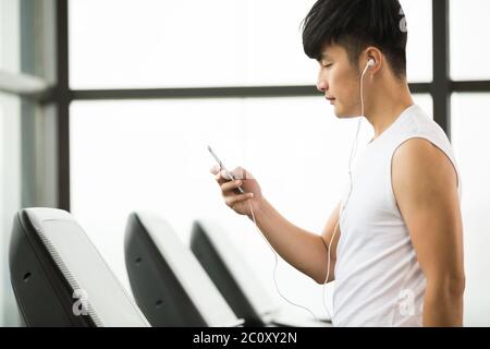 Die Jungen gut aussehenden asiatischer Mann sie ihr Smartphone in einen modernen Fitnessraum Stockfoto