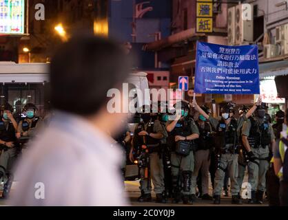 Die Bereitschaftspolizei hält eine blaue Flagge, um die Demonstranten während der Demonstration zu warnen.Tausende von Hongkongern sangen am 12. Juni Protesthymne und skandierten Parolen in der Stadt, als sie den einjährigen Jahrestag der großen Zusammenstöße zwischen Polizei und demokratischen Demonstranten ansprachen. Stockfoto
