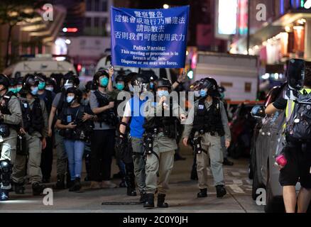Die Bereitschaftspolizei hält eine blaue Flagge, um die Demonstranten während der Demonstration zu warnen.Tausende von Hongkongern sangen am 12. Juni Protesthymne und skandierten Parolen in der Stadt, als sie den einjährigen Jahrestag der großen Zusammenstöße zwischen Polizei und demokratischen Demonstranten ansprachen. Stockfoto